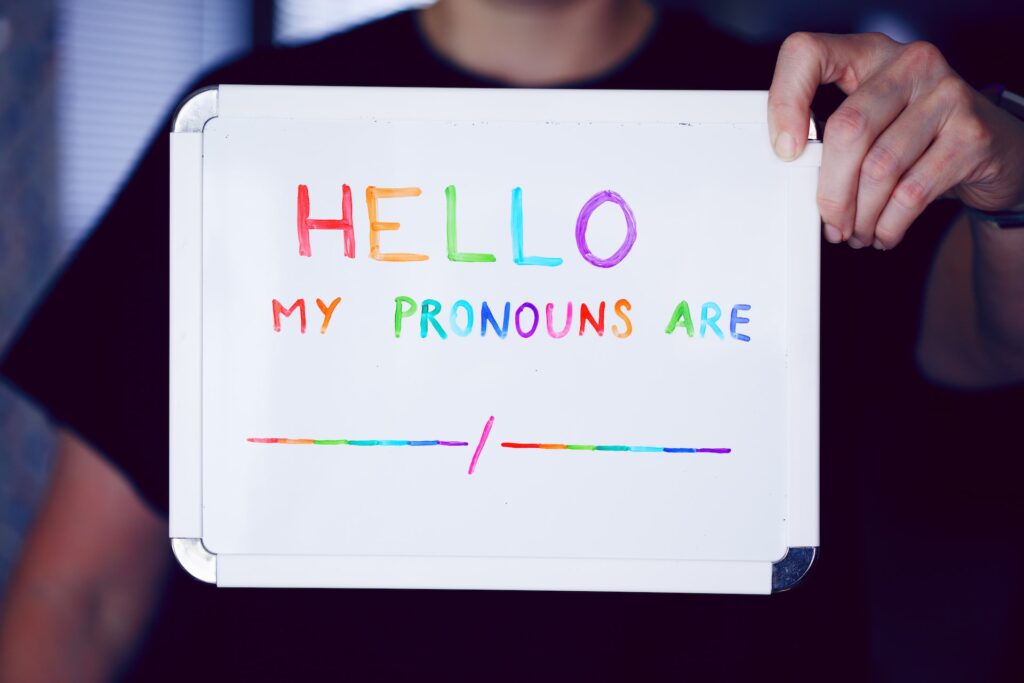 image of person holding a sign that says "Hello my pronouns are" 