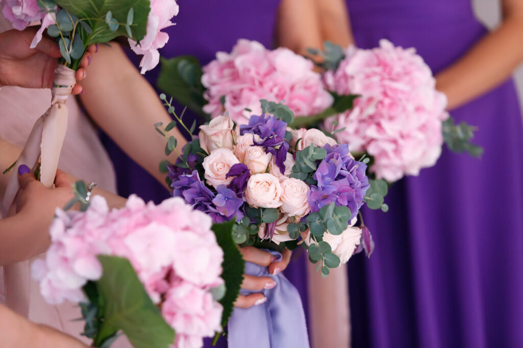 Row of bridesmaids and bride in violet dresses with bouquets at wedding ceremony