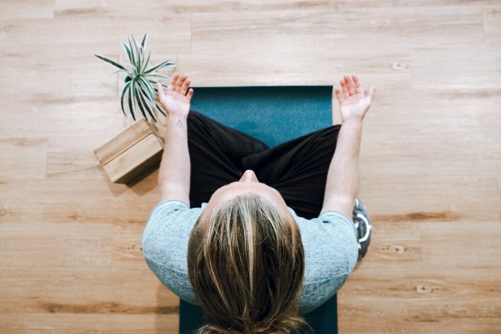 Woman sitting on yoga mat with palms up.