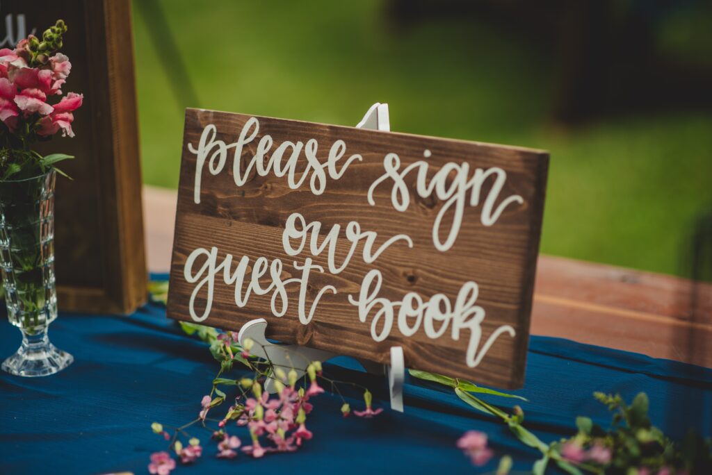 Wooden sign reading quote please sign our guest book end quote