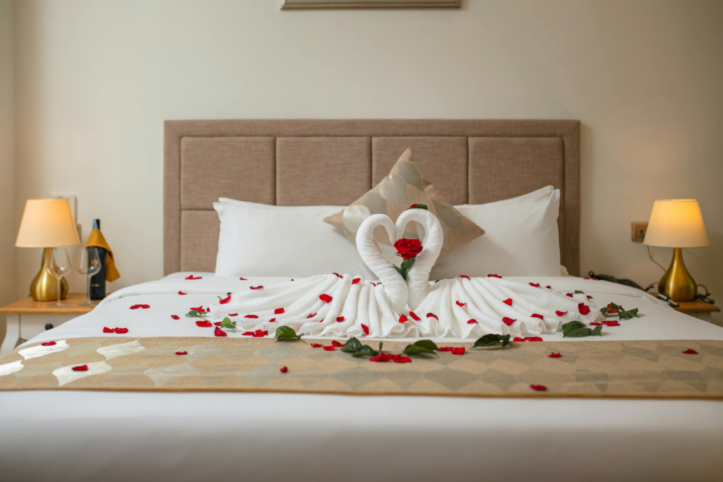 Swan towels on a hotel bed with rose petals 