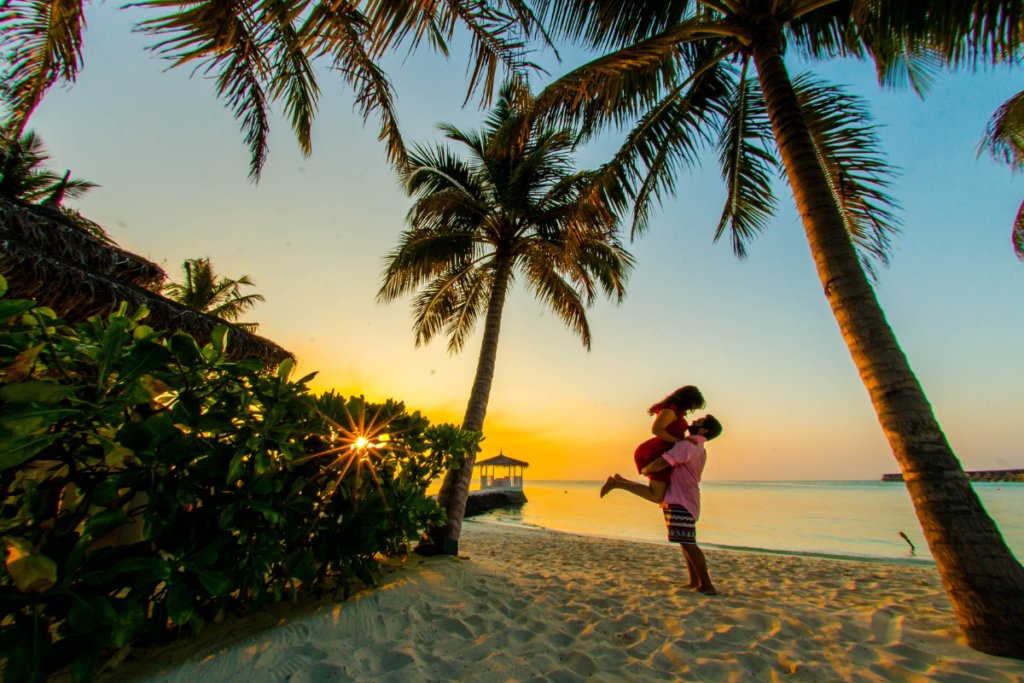 Man and woman couple embracing on a tropical beach during sunset