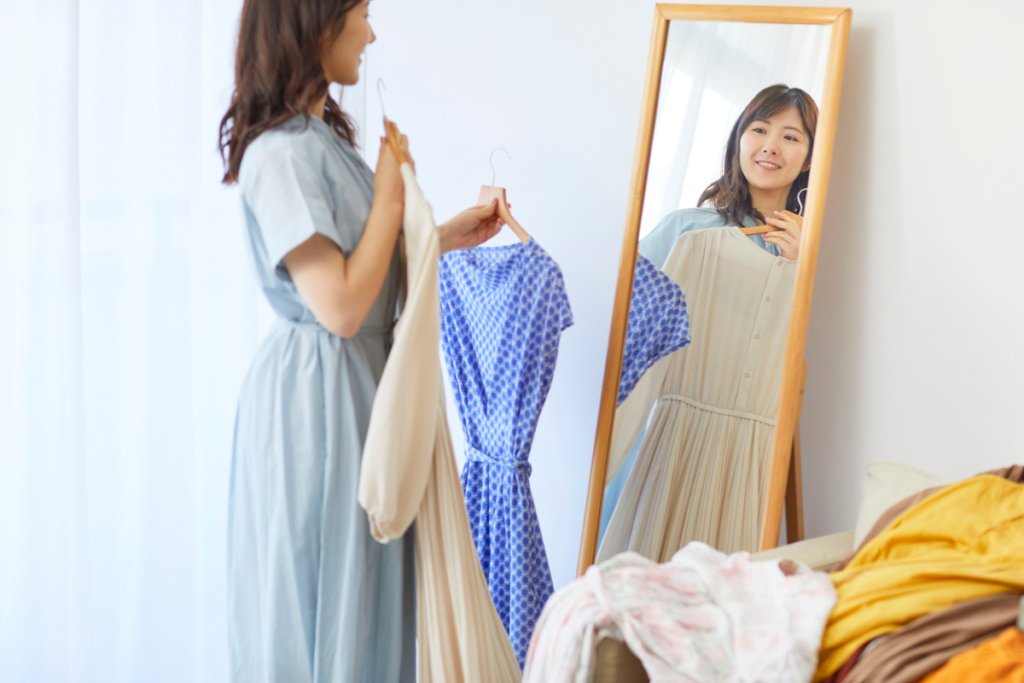 Woman holding up dresses in front of a mirror