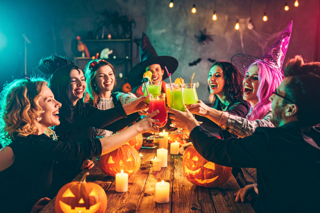 Men and women dressed in Halloween costumes "cheersing" around a wooden table.