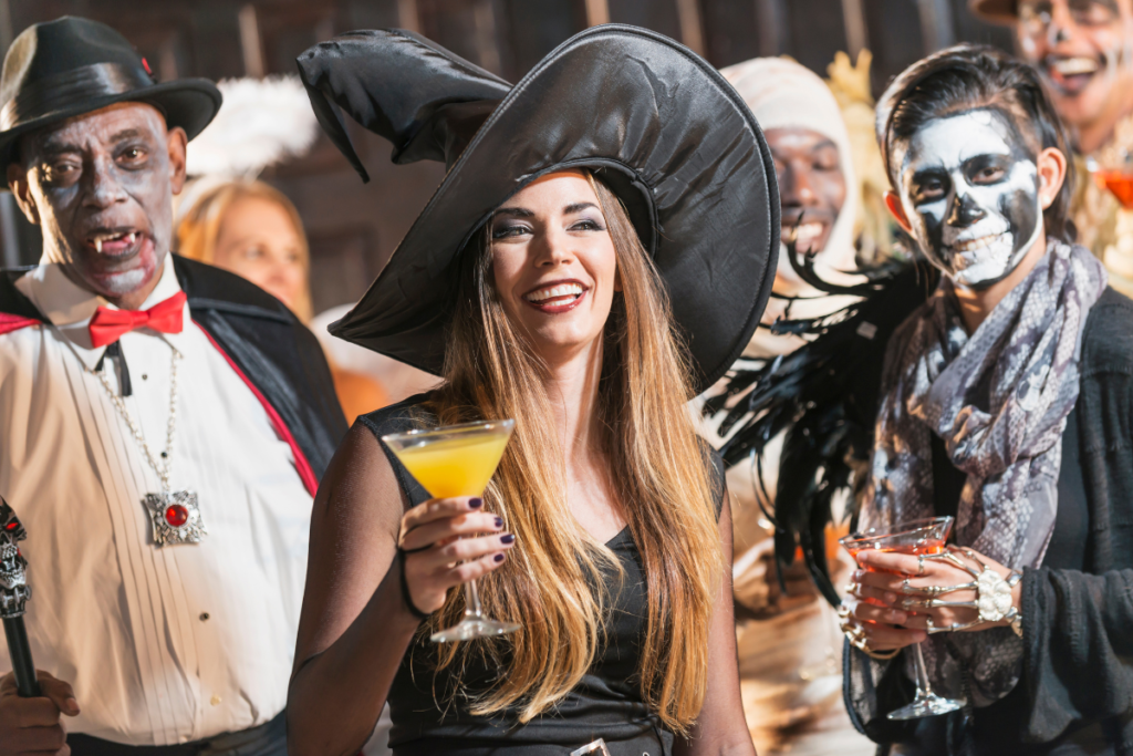 Men and women dressed in Halloween costumes holding drinks