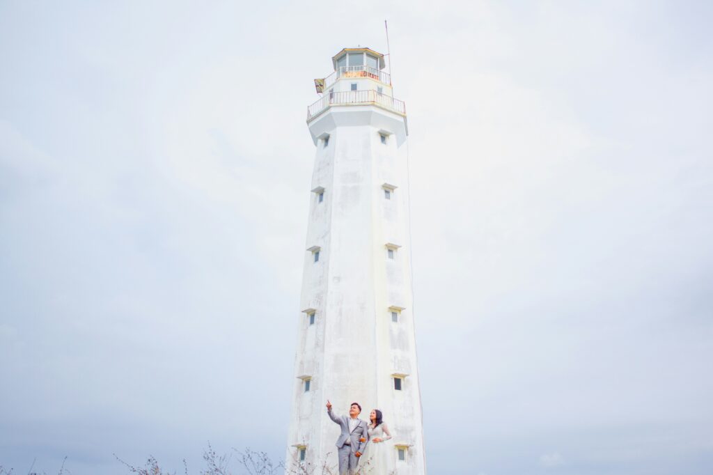 Bride and groom standing in front of a lighthouse on a foggy day