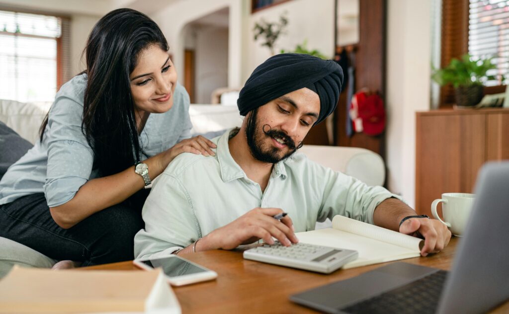 Man and woman looking at a budget with a calculator and laptop