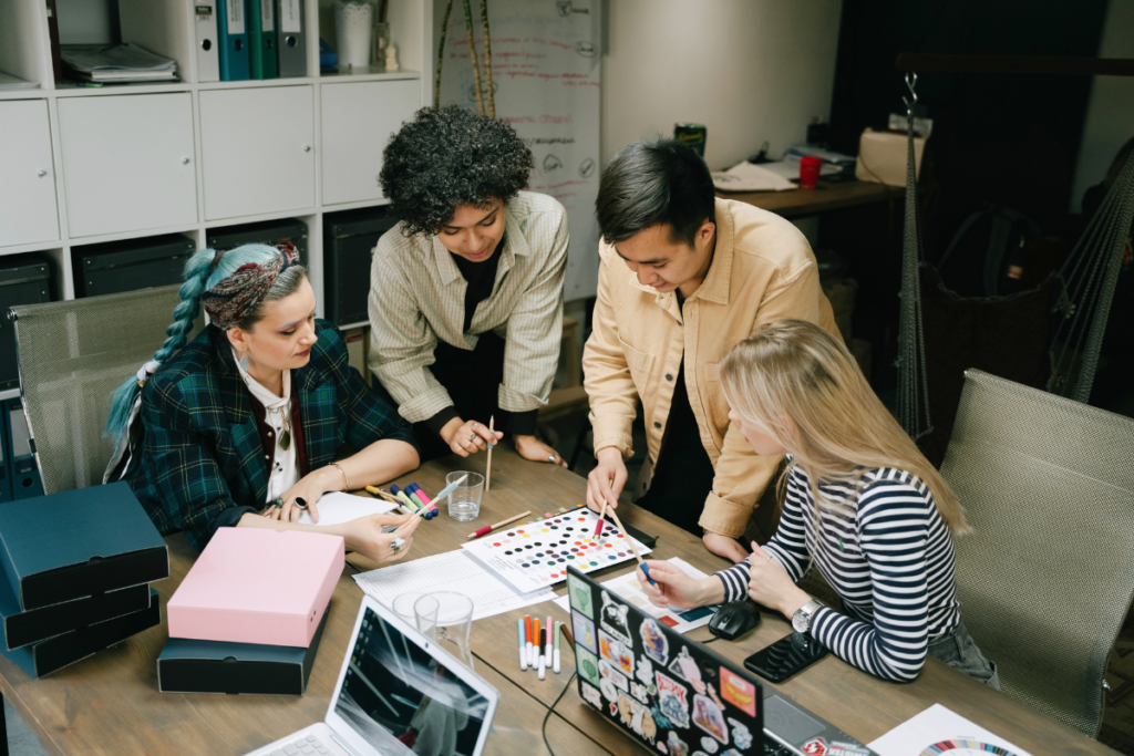 Men and women gathered around papers, collaborating on a project