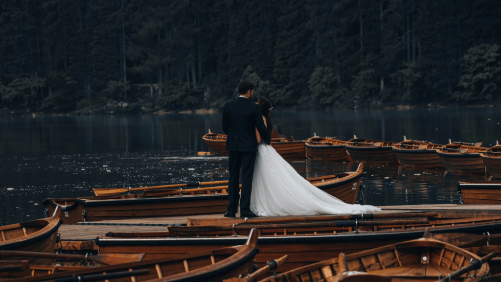 Bride and groom standing on a dock around old wooden boats