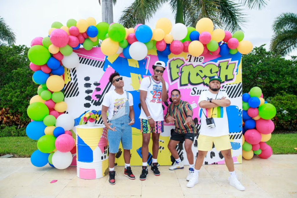Group of men posing by a party welcome sign