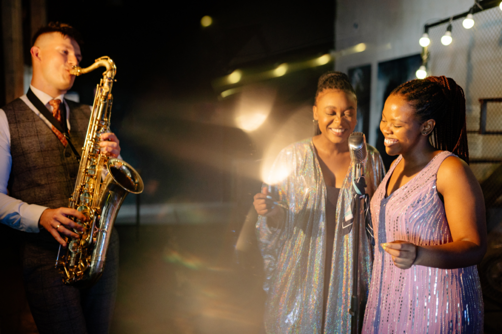 Two women dancing by a saxophone player