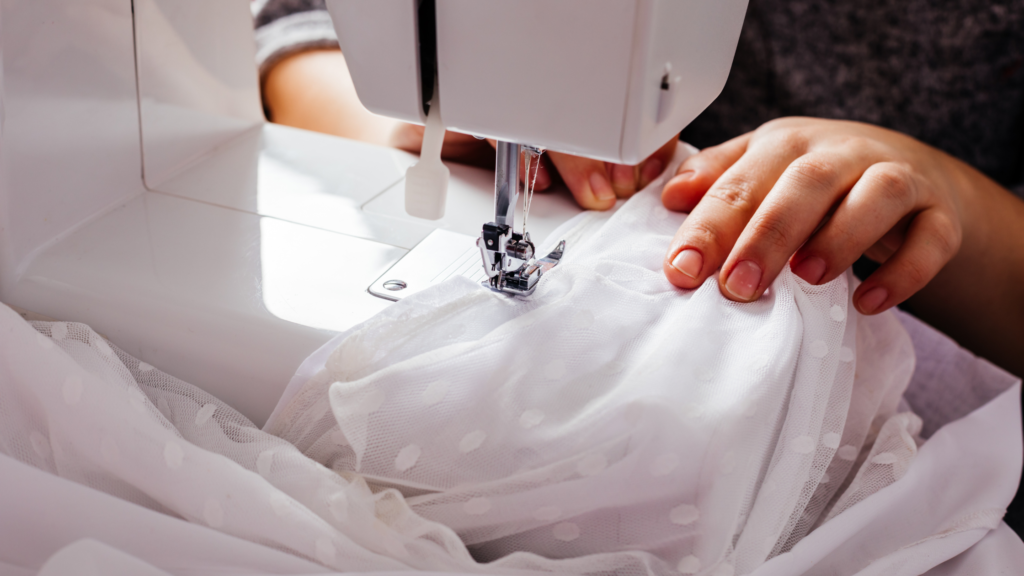 A person using a sewing machine on a white dress