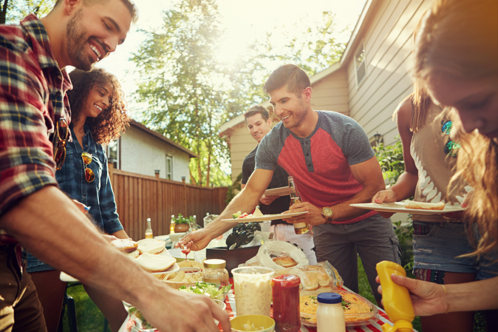 Adults at an outdoor BBQ getting food