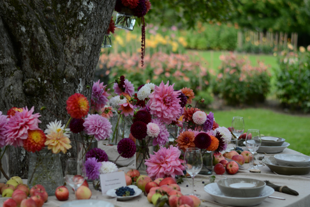 A dining table set up in a garden with floral arrangements